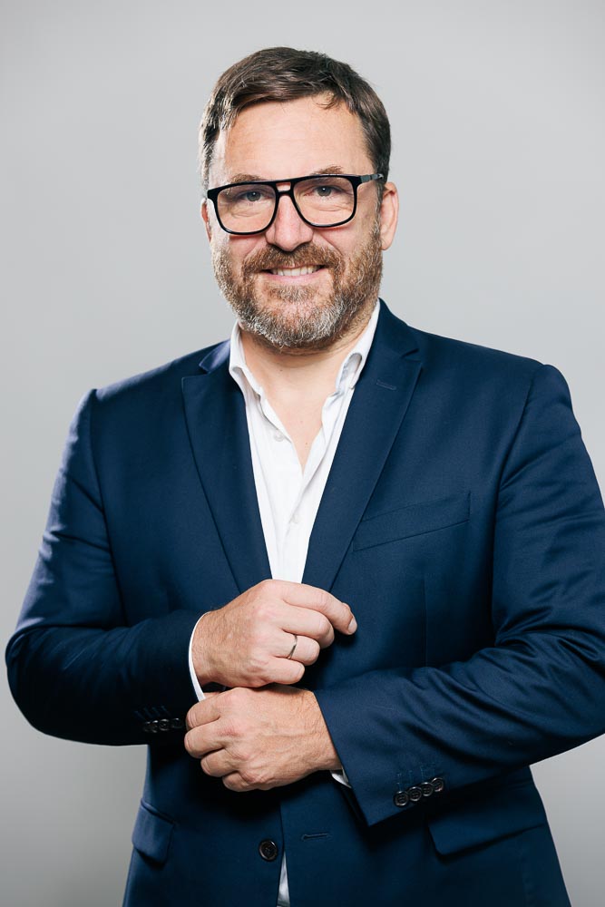 Homme souriant en veste professionnelle, valorisant son image pour le marché de l’emploi