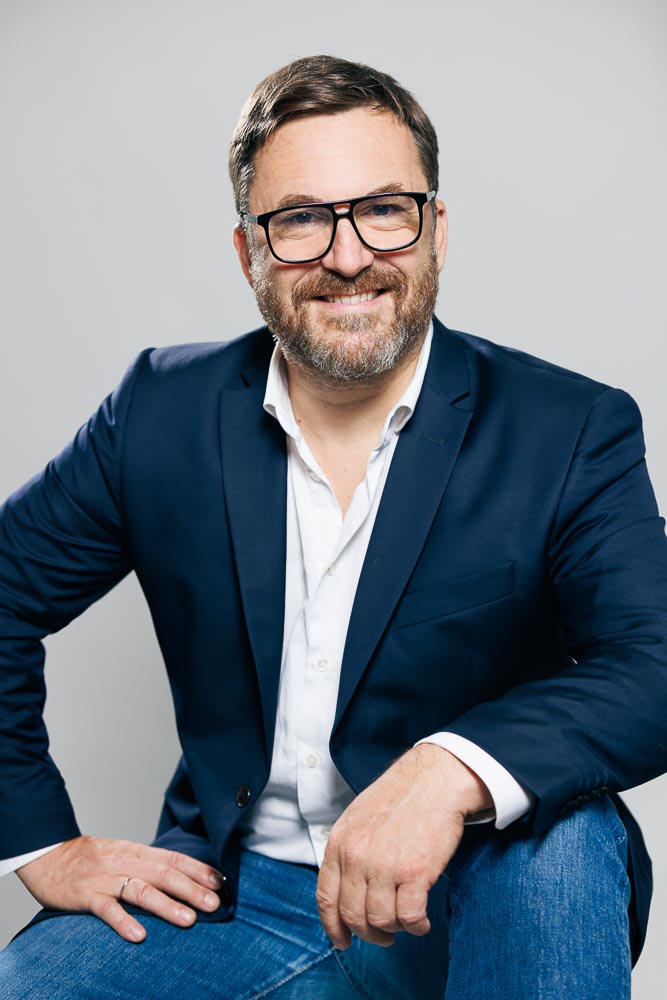 Homme élégant en tenue professionnelle posant en extérieur parisien pour CV