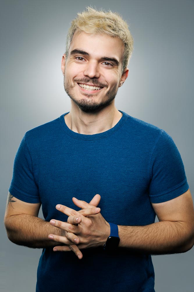 Profil masculin posé devant un fond uni, sourire accessible et regard direct pour CV digital