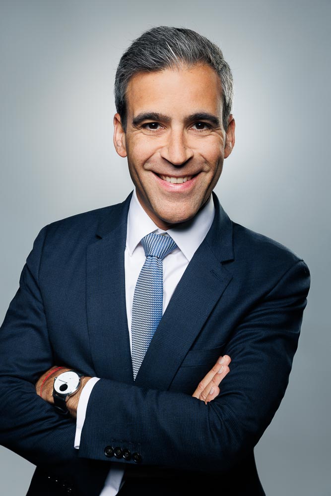 Souriant confiant en costume, fond simple et lumière équilibrée pour un rendu naturel