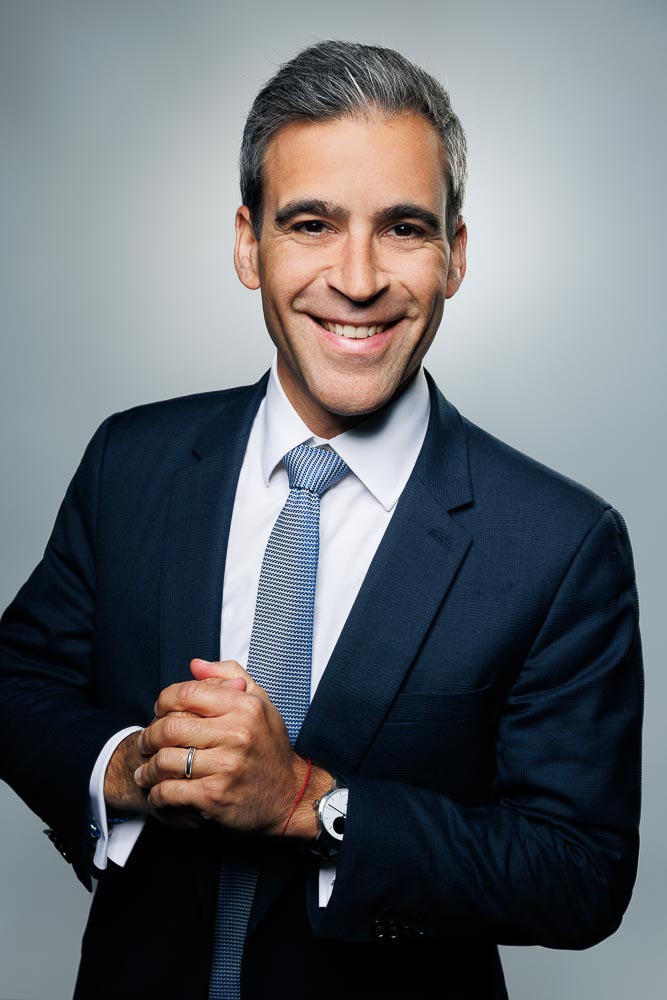 Portrait en plan rapproché d’un professionnel souriant et bien éclairé, fond sobre