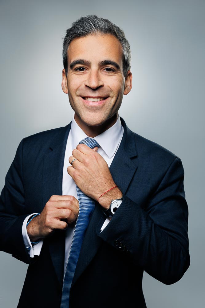 Portrait professionnel d'un homme en chemise bleue avec un sourire naturel et un fond neutre