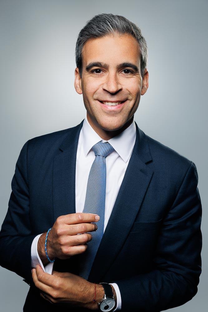 Regard direct et sûr dans un portrait présentant une tenue soignée et un fond discret