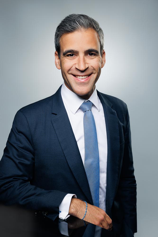 Visage souriant et professionnel, éclairé de manière équilibrée sur un arrière-plan uni