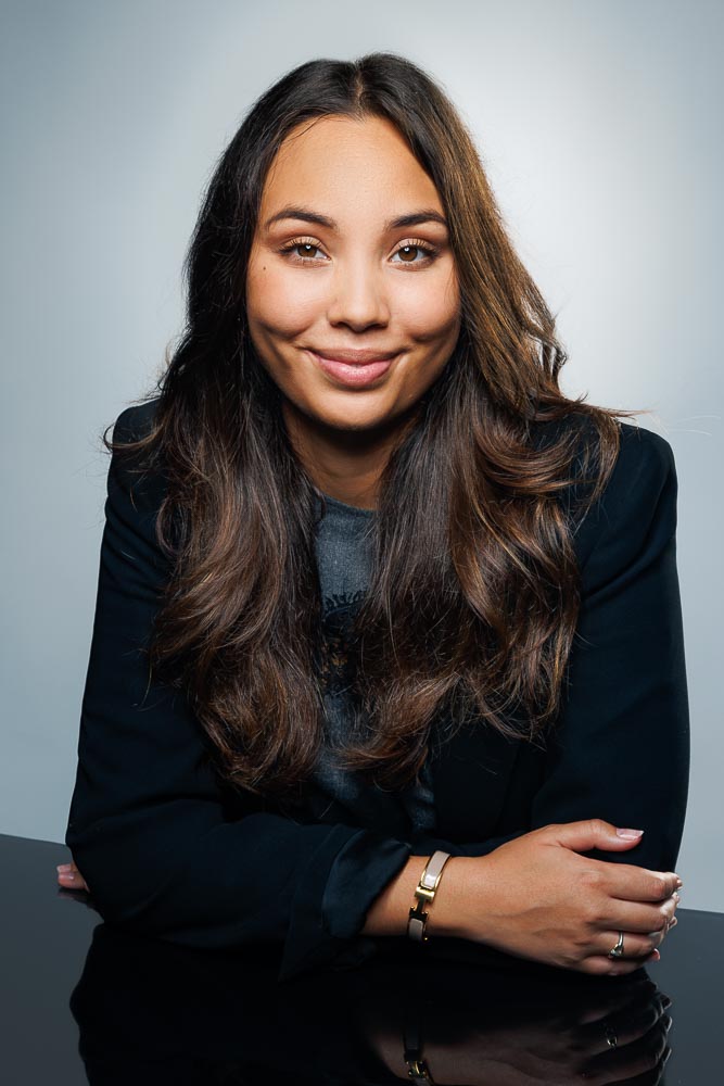 Visage d’Estelle éclairé avec finesse, présentation soignée et vêtements sobres.