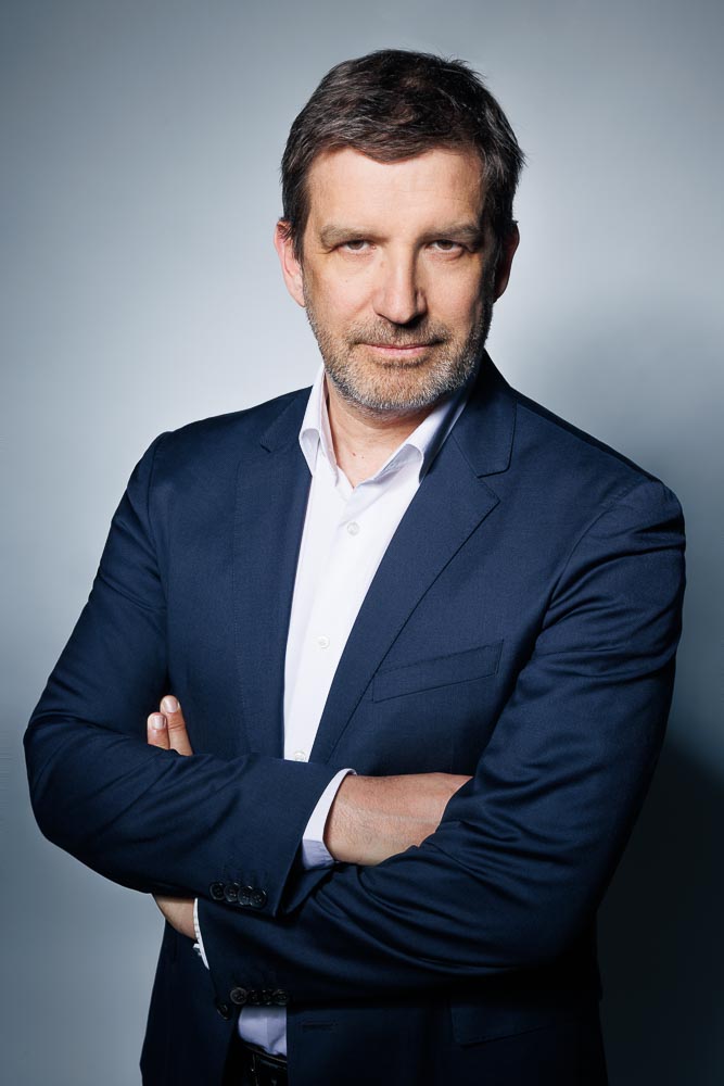 Portrait professionnel d'un CEO dans un studio parisien moderne et épuré, en tenue formelle.